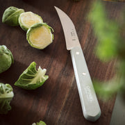 Opinel | Essential Small Kitchen Knife Sets, Fifties: A serrated knife on a cutting board with Brussels sprouts, ideal for versatile kitchen use.