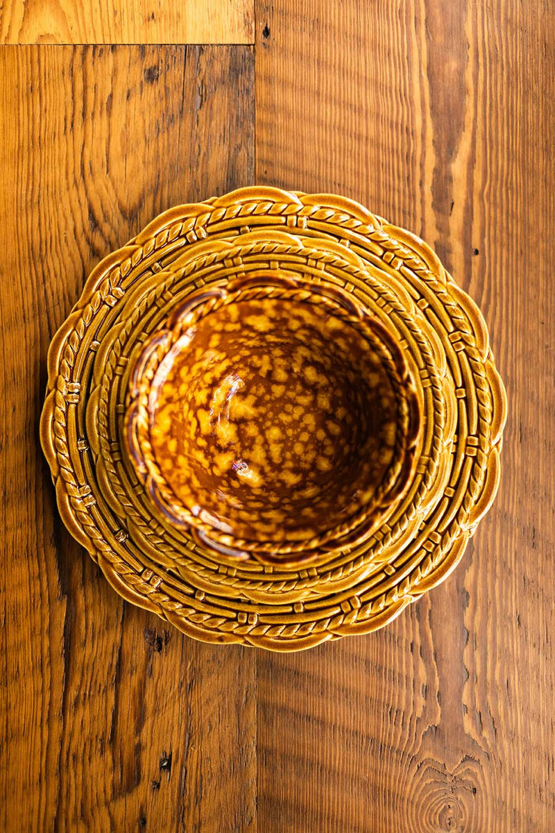 Provvista Designs | Basket Jubilee Cereal Bowl in Honey Tortoise, featuring a scalloped rim and braided border plate, on a wooden table.
