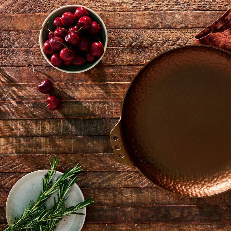 Smithey Farmhouse Skillet showing hammered rim beside cherries and herbs
