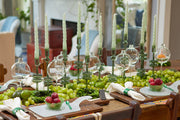 Etú Home | Clear Wine Glass Vase Medium featured as a table centerpiece with grapes and candles, showcasing its elegant design perfect for weddings or dinner parties.