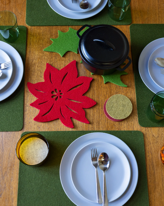 Graf Lantz Merino Wool 10 Poinsettia Trivet on a table set with plates and utensils, adding a festive, protective touch to the dining setup.