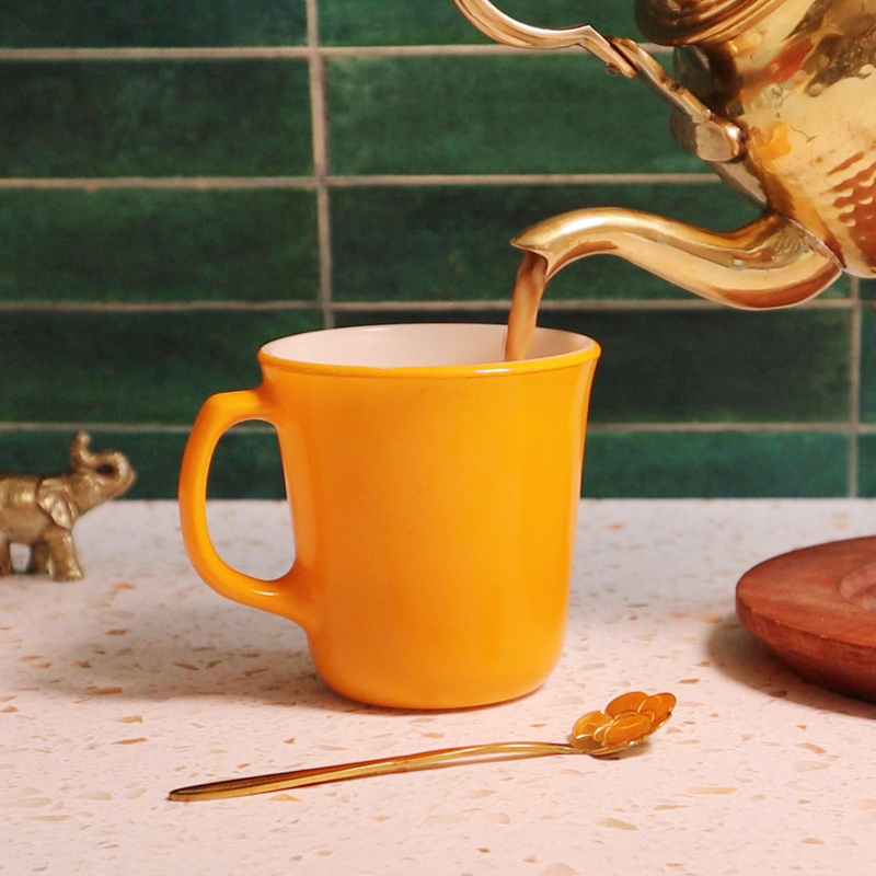 Spicewalla | Chai Pani Ginger Chai being poured into a yellow mug, accompanied by a flower-shaped spoon, capturing the essence of cozy, flavorful tea moments.