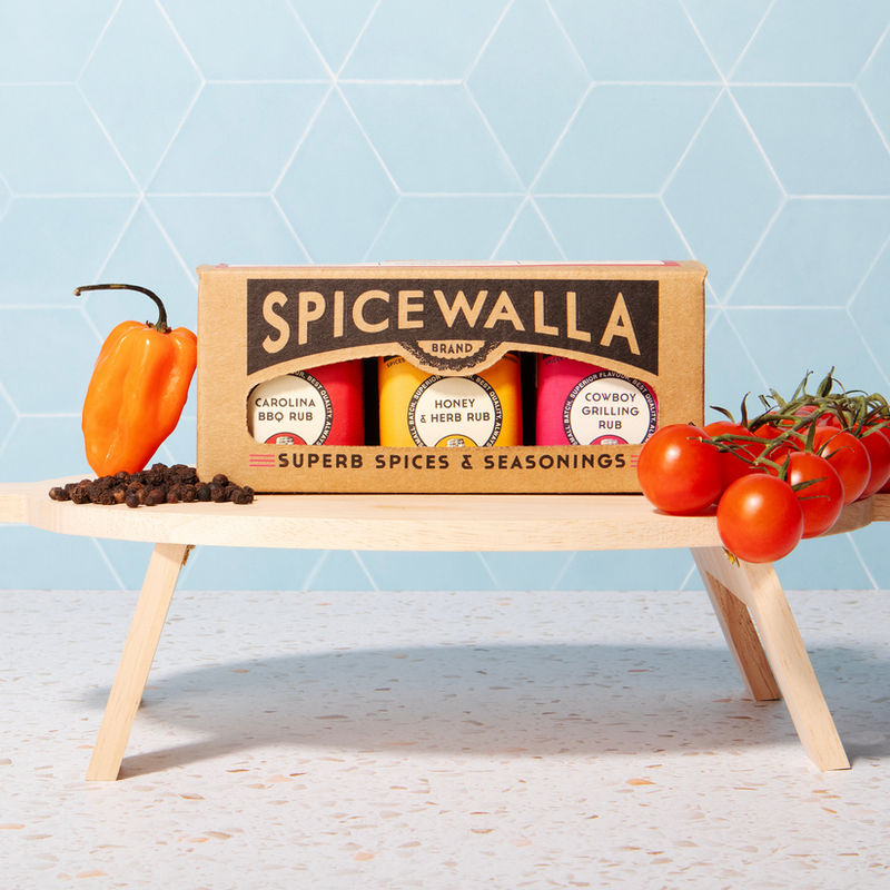 Spicewalla Grill & Roast 3 Pack gift box with Carolina BBQ, Honey & Herb, and Cowboy Grilling rubs, displayed with a habanero, peppercorns, and cherry tomatoes.