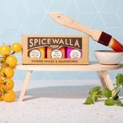 Spicewalla | Ultimate Backyard BBQ Collection - 3 Pack displayed with a basting brush, ceramic bowl, cherry tomatoes, and cilantro, highlighting three BBQ rub jars.