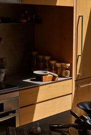 Holcomb Studio Perch Mortar & Pestle on kitchen counter, featuring granite stone and ash wood base for efficient grinding of spices and herbs.