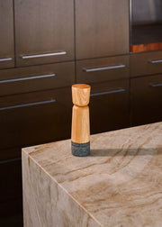 Holcomb Studio Stone Pepper Mill on a countertop, showcasing its sleek wooden design, ideal for enhancing any kitchen tool collection from Athens Cooks.