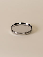 Holcomb Studio Puddle Coasters, Set of Four: Polished stainless steel coasters with anti-slip pads, designed to protect surfaces from condensation and spills, stackable for easy storage.