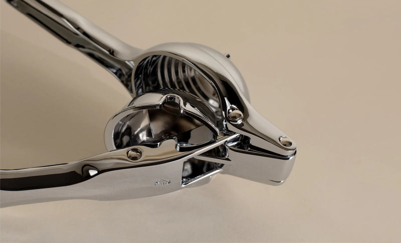 Holcomb Studio | Link Citrus Press: A sleek, shiny silver metal tool designed for efficient citrus juicing, perfect for enhancing your kitchen experience.