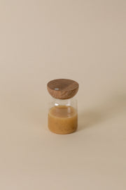 Holcomb Studio | Totter Salad Dressing Shaker: A glass jar with brown liquid and a wooden lid, ideal for mixing and serving dressings.