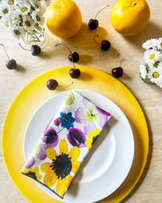 Floral printed napkin set by Tisch New York, displayed on a plate with citrus fruits. Set of four, 18x18 inches, pre-washed linen.