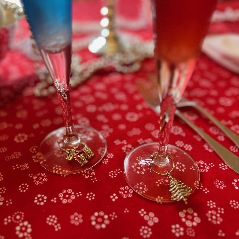 Joanna Buchanan Christmas Wine Charms adorning two wine glasses on a table, showcasing elegant barware ideal for festive gatherings.