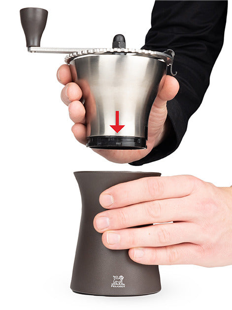 Peugeot | Kronos Coffee Mill, 7.5 inches, being assembled; the stainless-steel top with crank connects to the base, showcasing the Peugeot lion logo.