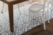 Liberty L Italian Vinyl Rug on display with a white chair and table, embodying Italian design with a functional, water-resistant, anti-slip surface. Perfect for indoor styling.