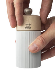 Peugeot | Line Pepper Mill Aluminum + Beechwood, Natural, 4.75 Inches, with a wooden top and ribbed aluminum body, held by hands, showcasing its adjustable grind setting.
