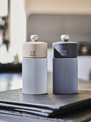 Peugeot Line Pepper Mill, 4.75, with beechwood top and ribbed aluminum body, featuring the Peugeot lion logo, showcased on a dark surface.