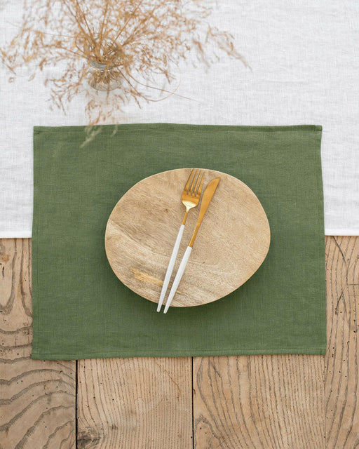 MagicLinen | Linen Placemats - Cinnamon - Set of 2, elegantly enhance a rustic table setting with a wooden plate, gold-tone cutlery, and a vase with dried wildflowers.