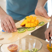 Opinel Medium Beech Wood Cutting Board in use for slicing fruit, showcasing its practicality for food prep and serving.