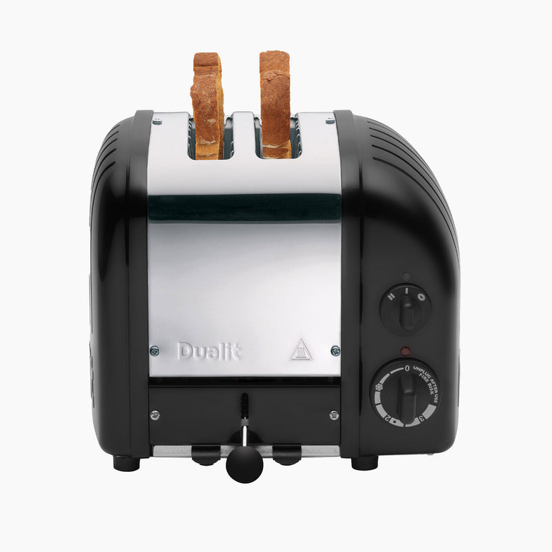 Dualit | 2 Slice Classic Toaster, Matt Black, with two whole-wheat bread slices ready, showcasing its quality craftsmanship and unique features like defrost and bun toasting options.
