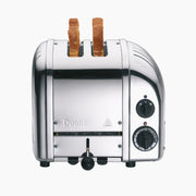 Dualit | 2 Slice Classic Toaster, Polished, featuring a stainless-steel finish with browning control knob, two bread slices inserted, and function settings visible on the side.