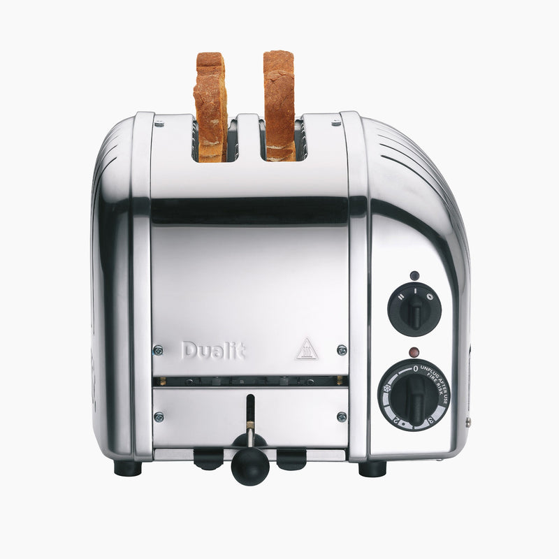 Dualit | 2 Slice Classic Toaster, Polished, featuring a stainless-steel finish with browning control knob, two bread slices inserted, and function settings visible on the side.
