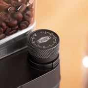 Moccamaster KM5 Burr Grinder with polished silver and matte black finish, featuring a stepless adjustment knob and static-reducing spout for uniform coffee grinding.