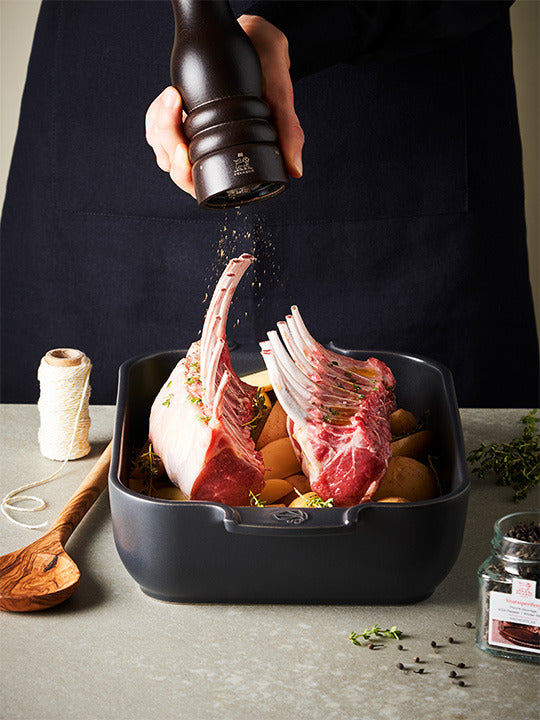 Peugeot | Paris u'Select Wood Pepper Mill Chocolate, 12 inches, held over lamb racks, grinding pepper onto herbs and potatoes in a roasting tin.