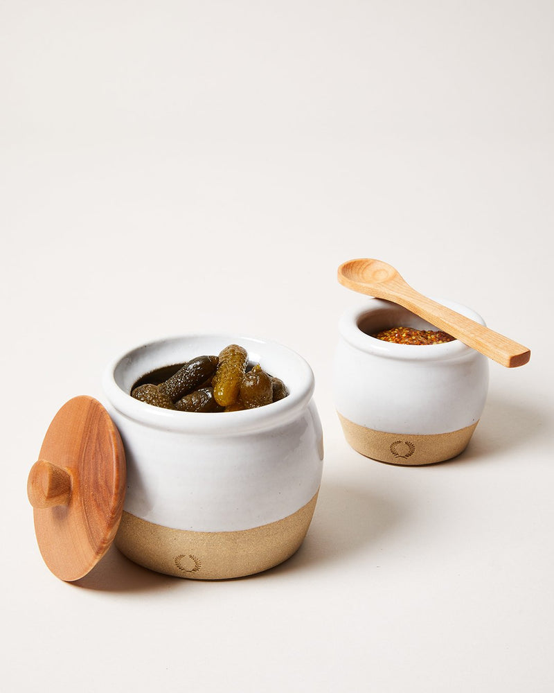 Farmhouse Pottery | Pickle Pot: Two hand-crafted ceramic crocks with pickles and mustard, highlighted by their unique textures and wooden accessories, perfect for rustic kitchen charm.