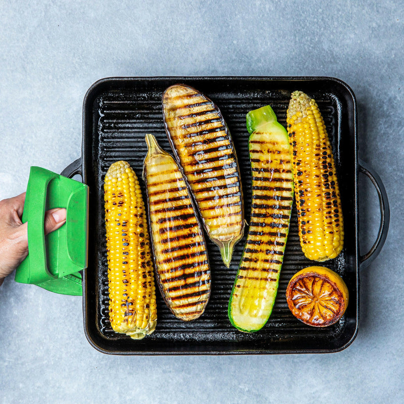 WOW GEAR | Gripmitt - Green shown handling grilled corn and zucchini on a grill pan, illustrating its versatility and safety in food preparation.