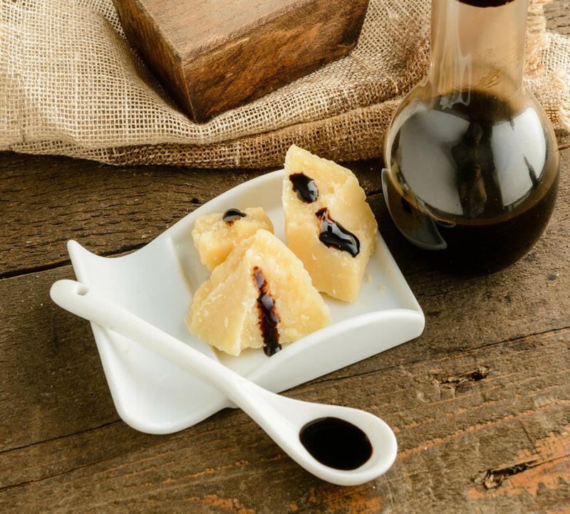 Acetaia Leonardi | 16 Year Balsamic Vinegar displayed with food, plate, spoon, and glass flask, showcasing its rich, aged grape must origin.