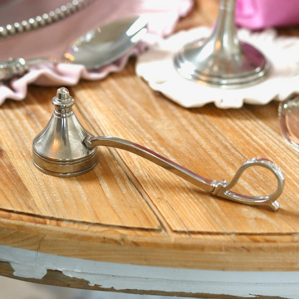 Arte Italica & Crown Linen Designs Lucia Snuffer—a handcrafted pewter candle snuffer with a looped handle, elegantly resting on a wooden tabletop.