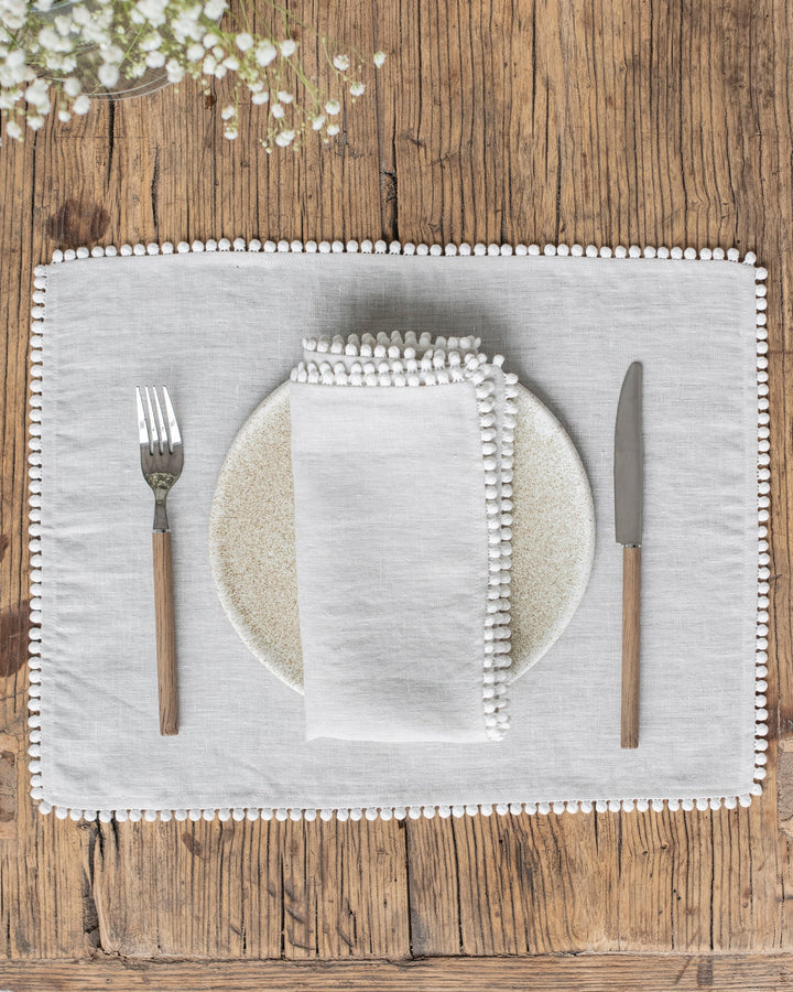 MagicLinen | Pom Pom Trim Linen Napkins - Light Gray - Set of 2 enhance dining elegance with their chic design and soft, durable fabric from Athens Cooks.