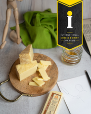 Beehive Cheese Co. LLC | Pour Me A Slice - 4 oz Wedge on wooden surface, showcasing its artful aging and bourbon infusion.