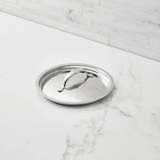 Hestan Provisions | Stainless Steel Lids Large, 12.5, resting on a marble countertop, showcasing its tri-ply construction and ergonomic handle for optimal cooking performance.