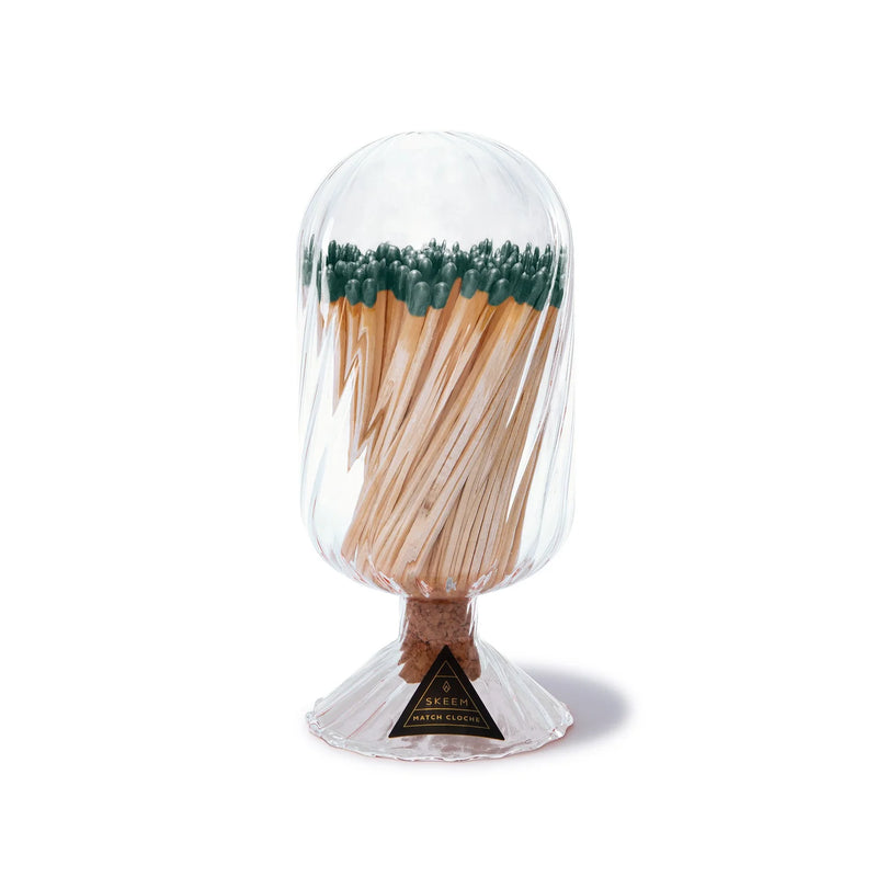 Skeem | Decorative glass cloche-style match holder on a fluted base with cork striker, containing long wooden matches with green heads, ideal for elegant kitchen or bar settings.