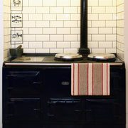 Earth & Nest | Red Range Towel hanging on a stove rail, featuring a popper fastening to prevent slipping, ideal for keeping towels clean and dry.