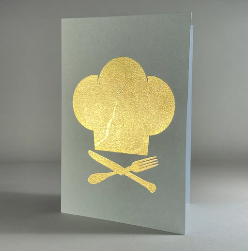Catherine Greenup Cards | Chef Hat on Moss: A greeting card featuring a gold-foil chef's toque with crossed utensils, perfect for culinary-themed gifting from Athens Cooks.