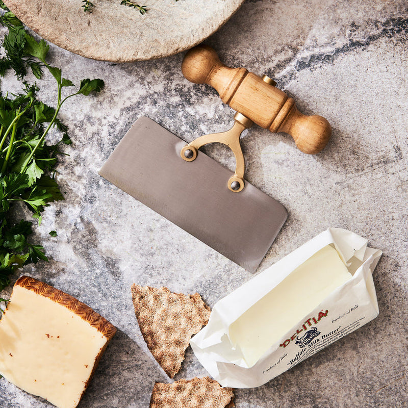 Sir|Madam Straight-Edge Scullery Chopper with wooden handle on a countertop, surrounded by Buffalo Milk Butter, cheese wedge, crispbread, and fresh herbs. Ideal for versatile kitchen tasks.