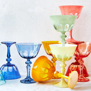 Sir/Madam Rialto glassware styled on a table in mixed colors including Honeydew green, with tumblers and coupes