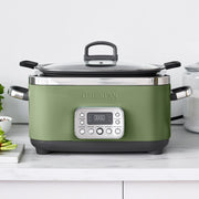 GreenPan multi-cooker with glass lid and digital controls, on a kitchen countertop, next to a cutting board and glass canister. Perfect for diverse cooking needs.