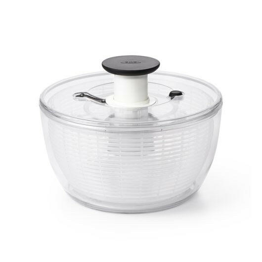 OXO Good Grips Salad and Herb Spinner with soft non-slip knob and built-in brake, ideal for drying and serving greens effortlessly in a kitchen setting.