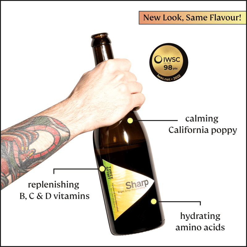 Three Spirit | Blurred Vines Sharp non-alcoholic aperitif bottle held by tattooed hand, highlighting calming poppy, vitamins, and amino acids, awarded 98 points by IWSC.