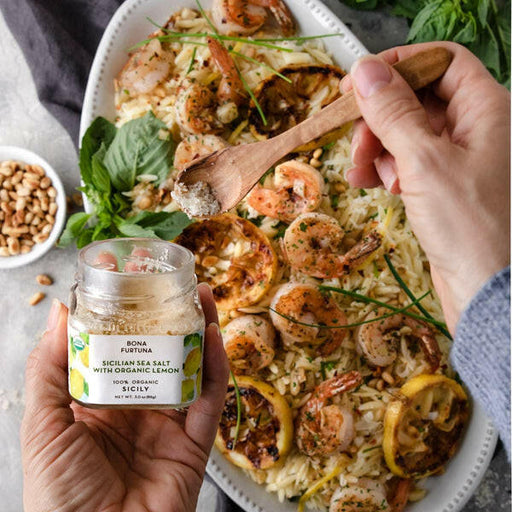 Close-up of a hand holding Bona Furtuna's Mama Rose's Herb Blend jar, highlighting its artisanal Sicilian seasonings crafted for enhancing various dishes.