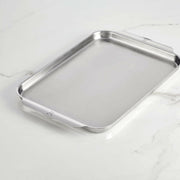 Hestan Provisions OvenBond Tri-Ply Bakeware - Medium Rack Only, featuring shallow sides and integrated handles, ideal for even baking and roasting on a light countertop.