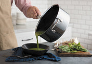 Pouring green soup into a black bowl from a Hestan NanoBond 4qt Saucepan, showcasing its precision pouring spout and ergonomic handle, ideal for culinary perfection.