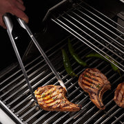 GrilLight | Gift Set - 2 Piece Spatula + Tongs in use, grilling meat with LED illumination on a barbecue grill.