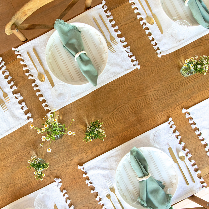 Sandy Stripes Original Flat Plate Liners artfully set on a table with white placemats and napkins, accented by a bouquet of white flowers.