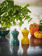 Peugeot | Bistro Pepper Mill, Saffron, alongside a green mill on a kitchen counter with parsley and bell peppers, reflecting Athens Cooks' curated kitchen essentials.