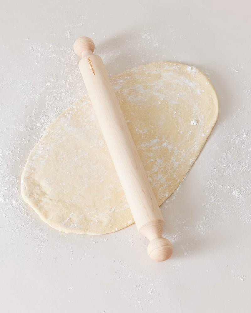 Farmhouse Pottery walnut rolling pin in use on a floured surface