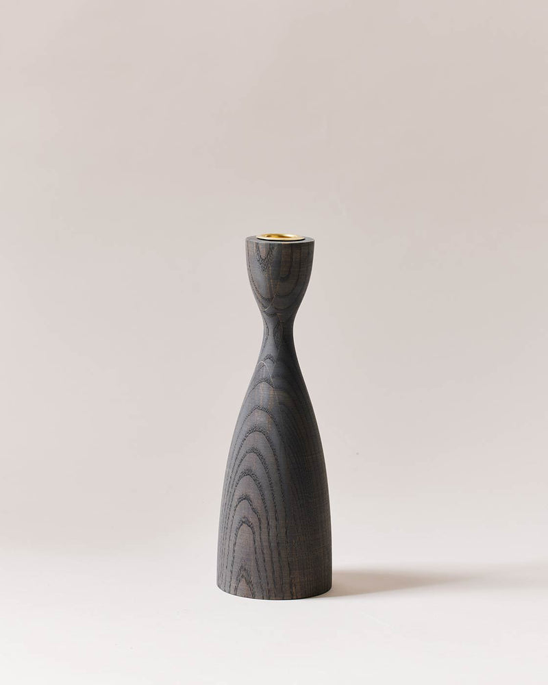 Farmhouse Pottery | Pantry Candlesticks - Medium Grey: A sculptural, dark-stained wooden candlestick holder with brass insert, showcasing an hourglass design and visible grain patterns.