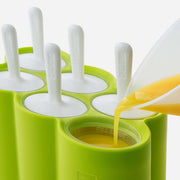 Zoku Classic Pop Mold with spoons and liquid being poured, ideal for creating homemade popsicles, showcased in a kitchen setting.